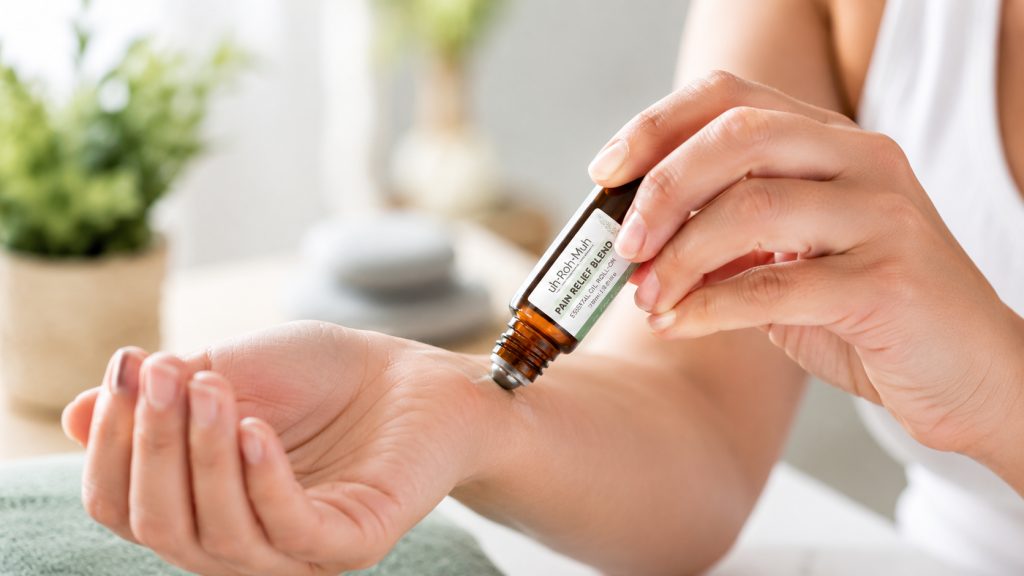 Applying natural essential oil pain relief blend to a sore wrist using a steel rollerball applicator